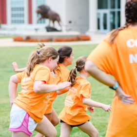 Three Girls on the Run participants are running at an outdoor practice in orange shirts